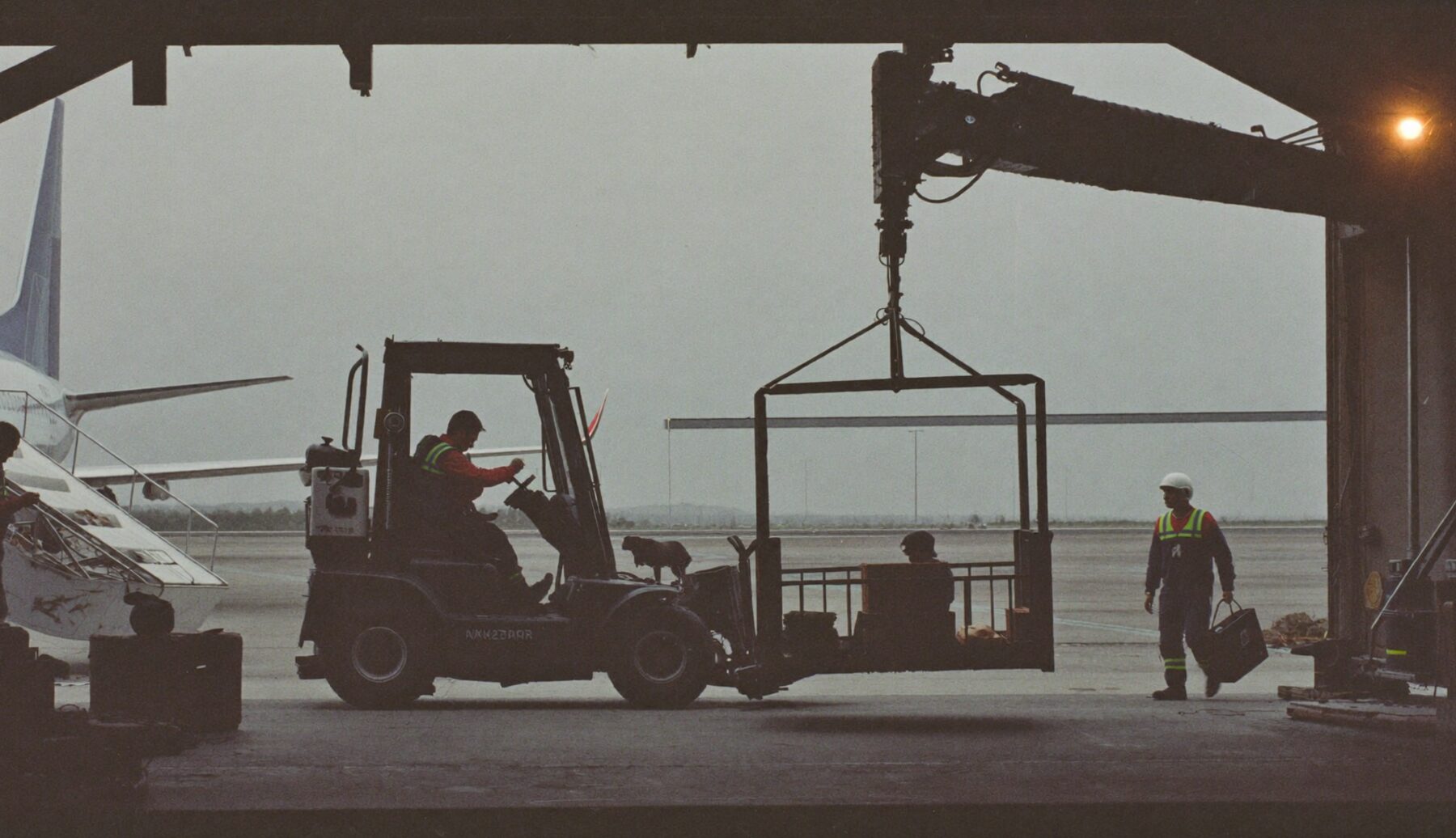 Ground crew lifting a pet crate gently toward an aircraft hold