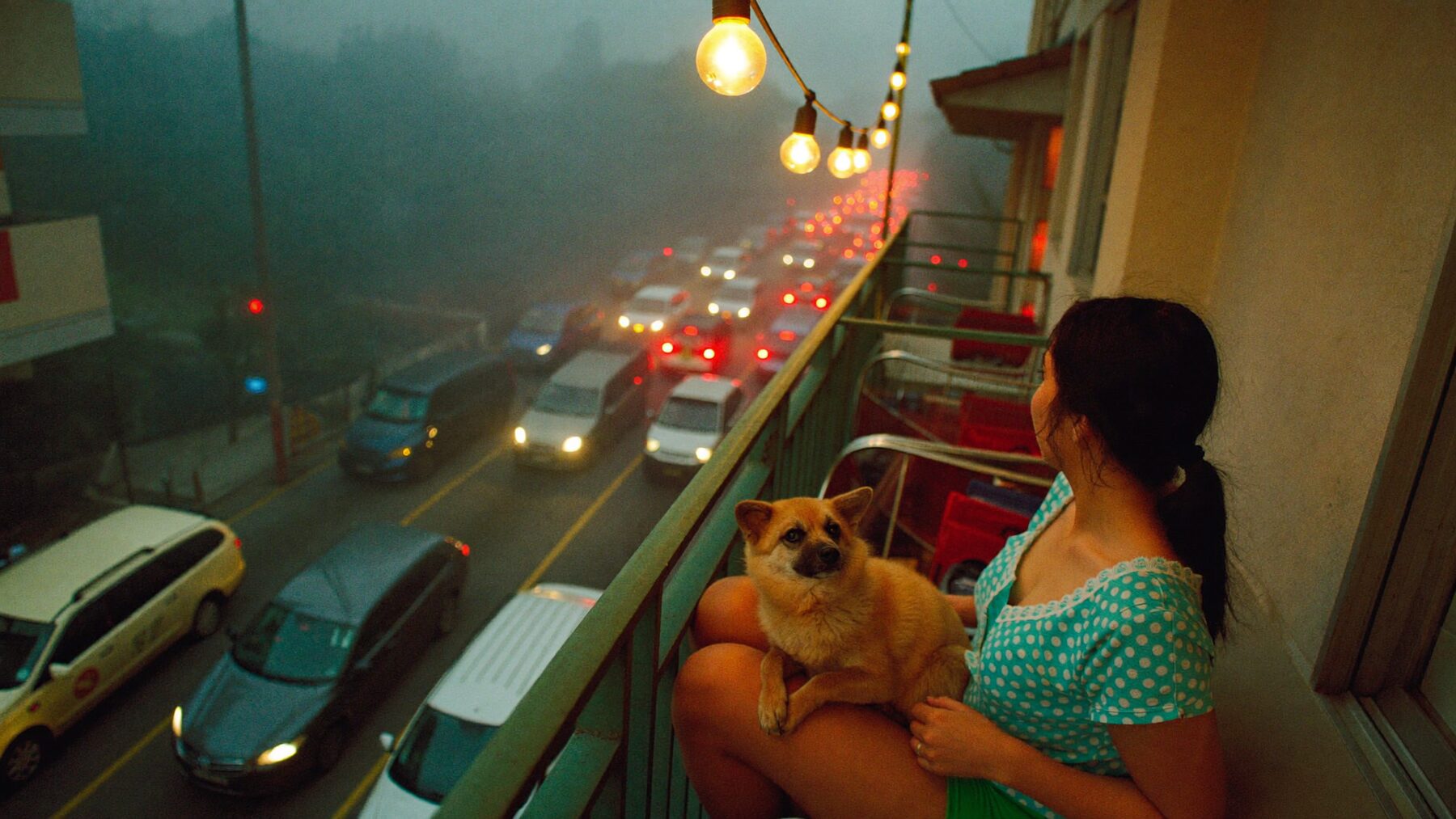 A woman with a small dog on her lap on a Manila balcony in the evening